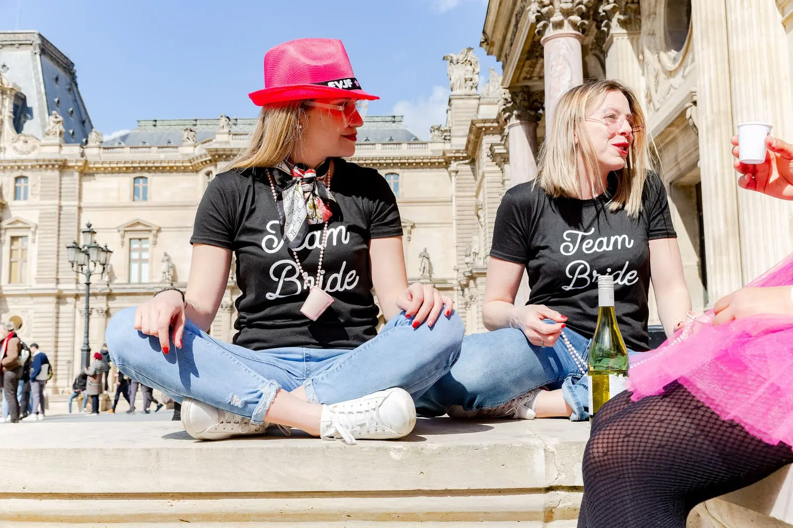Un groupe de filles assises à proximité des Pyramides du Louvre, discutent, pendant la séance photo EVJF.
