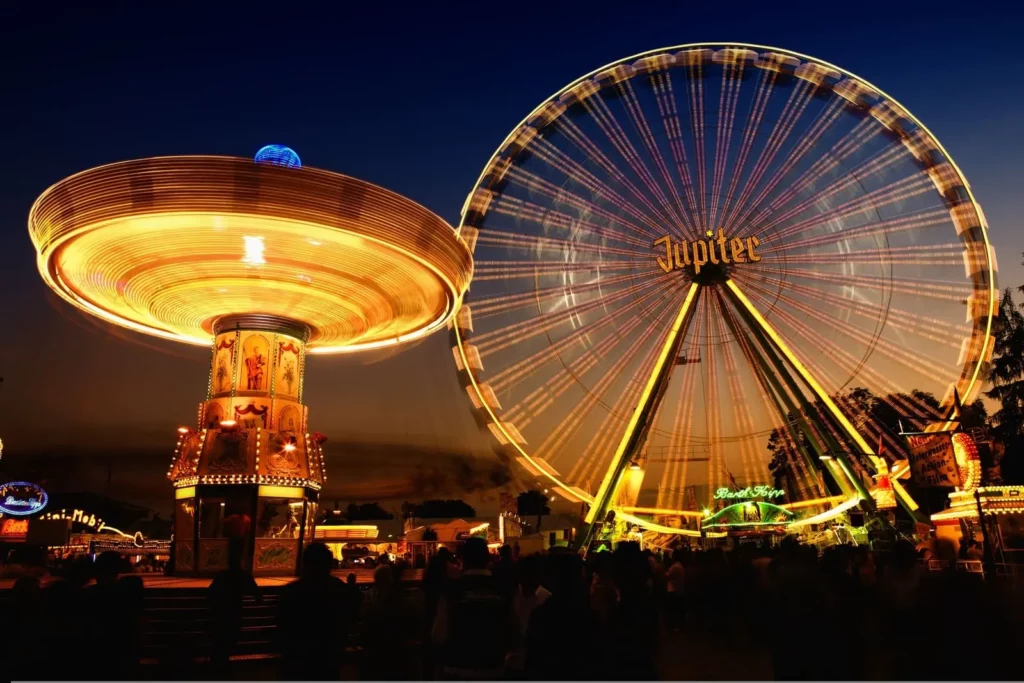 Photographie d'une grande roue et d'attractions, de nuit, en pose longue