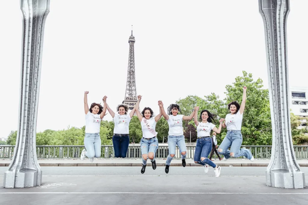 Un groupe de filles réalisent un saut synchronisé sur le pont Bir Hakeim à Paris, lieu de la séance photo EVJF.