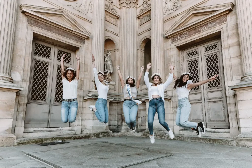 Un groupe de filles en jeans, baskets, t-shirts blanc et couronnes de fleurs sur la tête exécutent un saut synchronisé pour le shooting photo