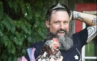 Photo d'humour : un homme déguisé en femme tenant une poule en référence à l'expression anglaise Hen Party