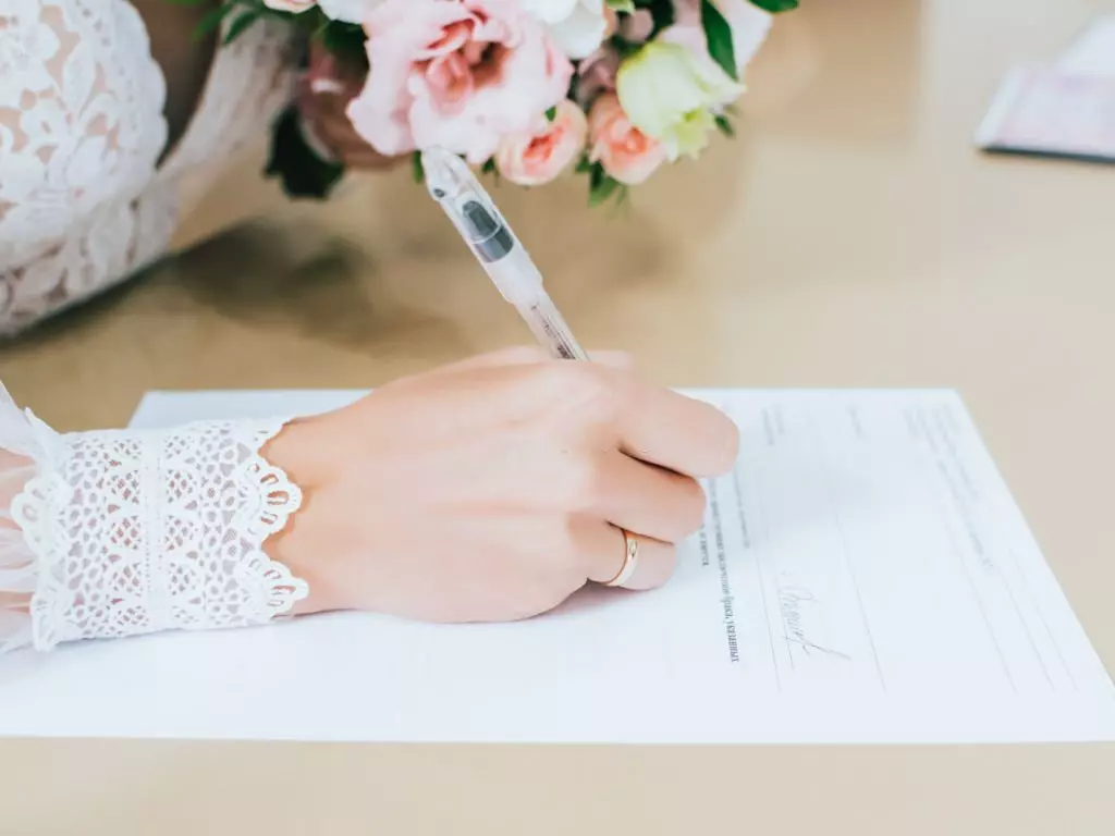 Photographie de la mariée qui signe les registres d'État civil à la mairie
