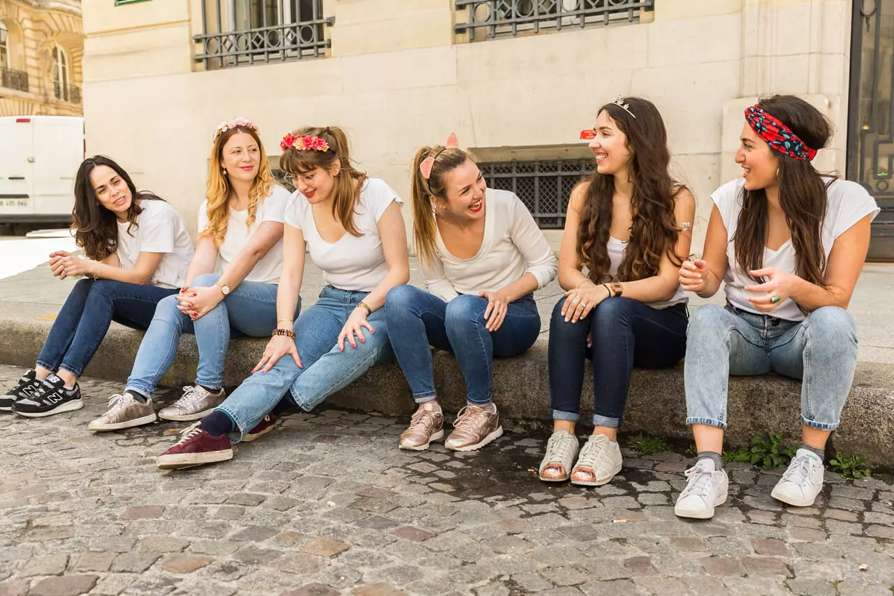UN groupe de jeune fille célèbre un evjf : elles portent des jeans, baskets, bandanas, diadèmes pour la mariée et couronnes de fleurs
