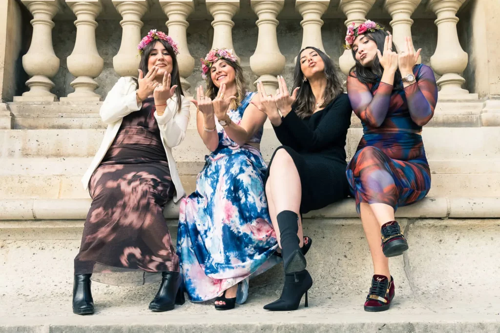 La mariée et ses demoiselles d'honneur en robe font le signe de Jul, pendant le shooting EVJF